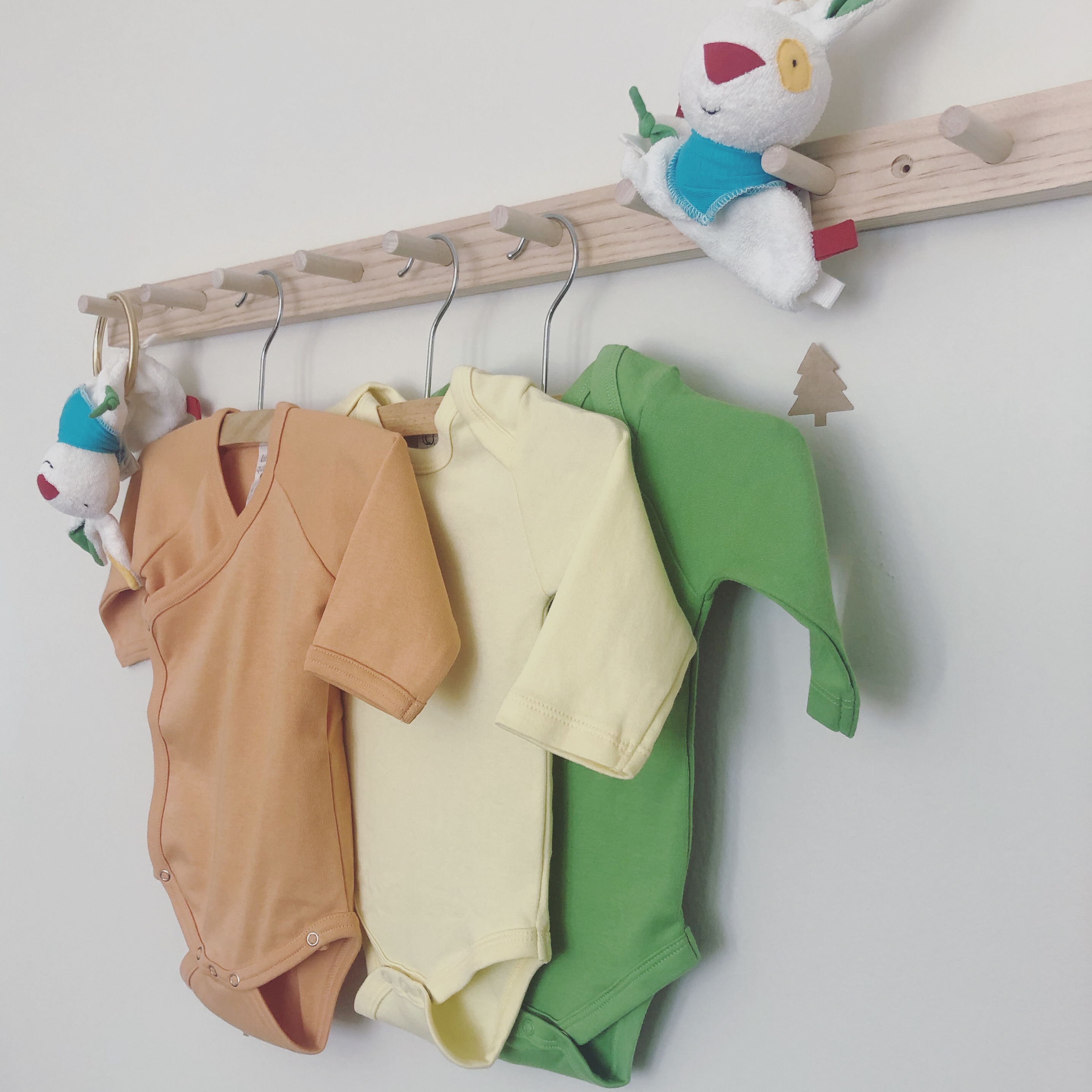 Colorful organic cotton baby bodysuits hanging on a rack
