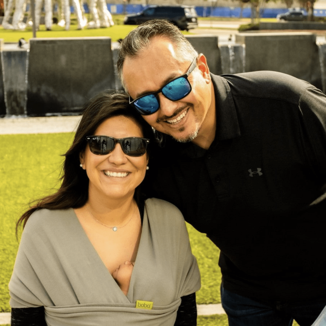 smiling parents in sunglasses leaning into each other