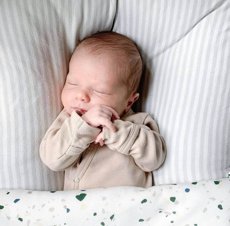 newborn sleeping wearing organic cotton onesie