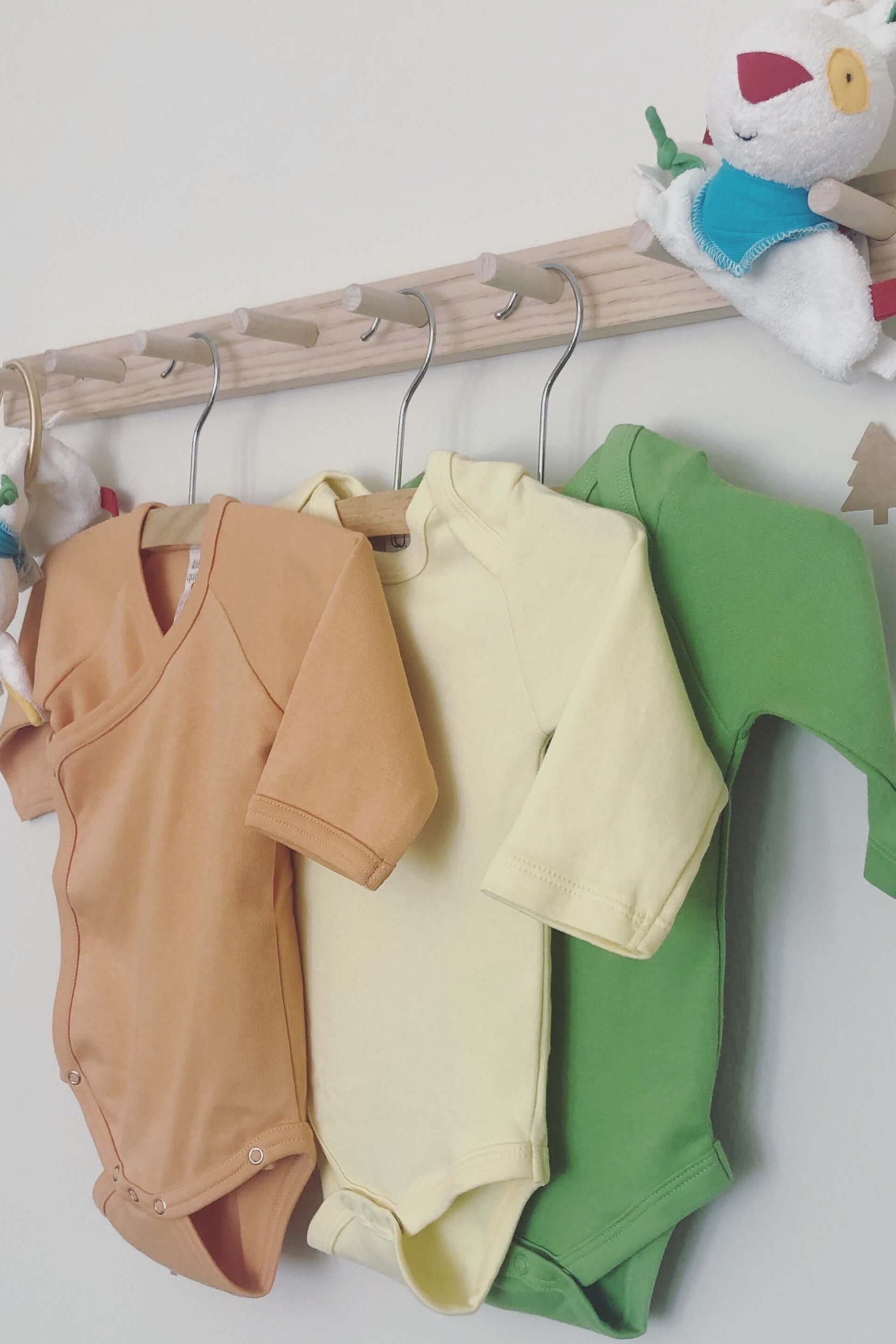 Colorful organic cotton baby bodysuits hanging on a rack