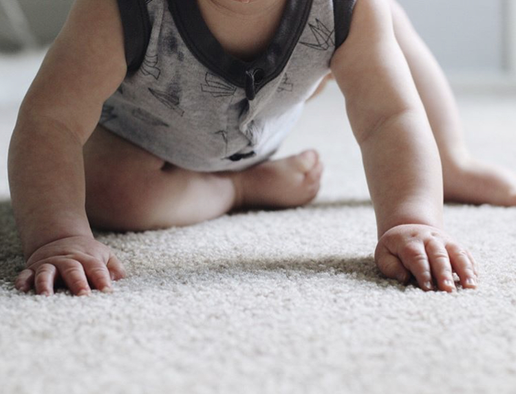 Baby sitting on carpet reading to crawl