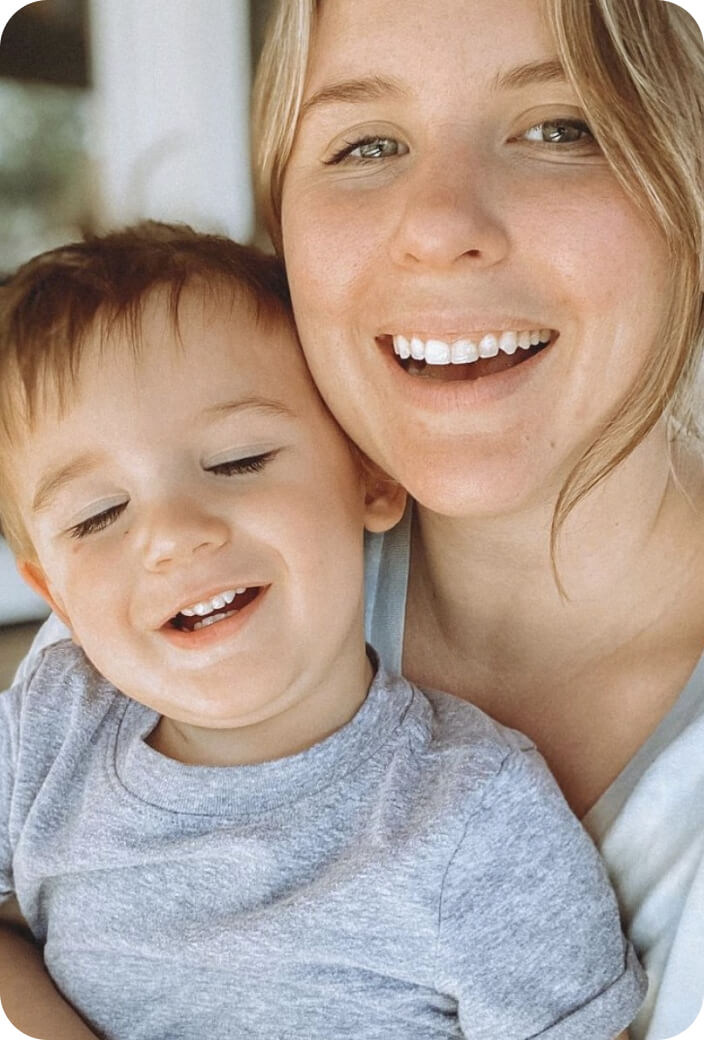 A mother and her baby boy smiling at the cameraa