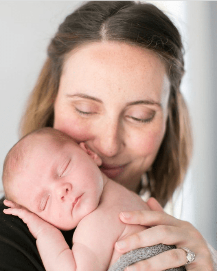 Smiling woman holding a sleeping newborn on her shoulder
